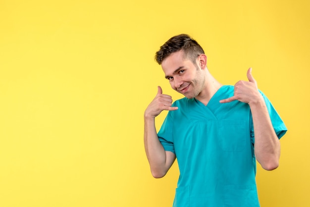 Front view of male doctor smiling on yellow wall