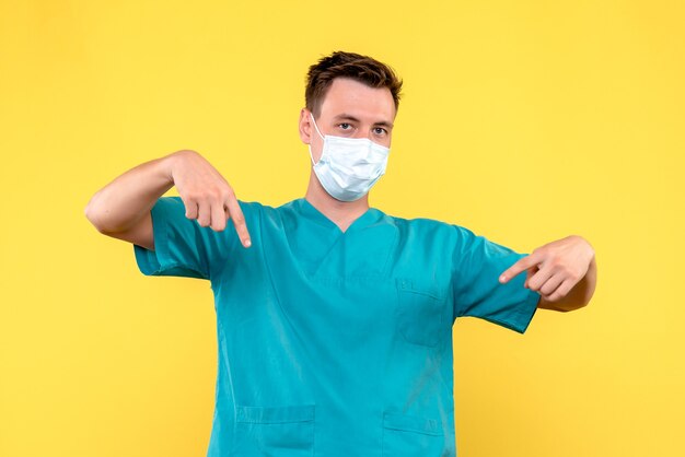 Front view of male doctor in sterile mask on yellow wall