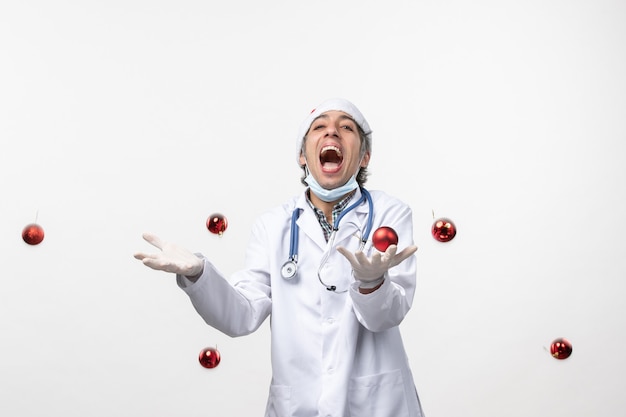 Free photo front view male doctor throwing toys on white wall virus covid health new year