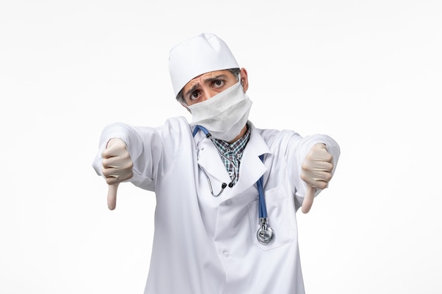 Free photo front view male doctor in white medical suit with mask due to covid on light white surface