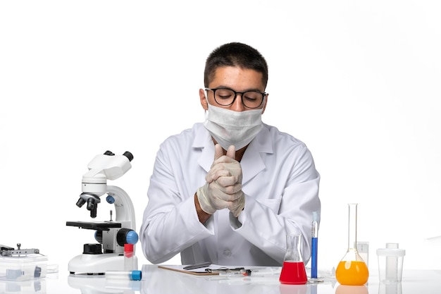 Front view male doctor in white medical suit with mask due to covid on white space