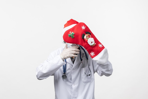 Free Photo front view male doctor with big red sock on the white wall virus covid- christmas