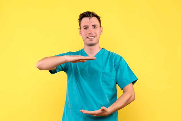 Front view of male doctor with smiling expression on yellow wall