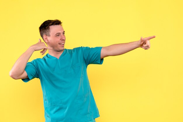 Front view of male doctor with smiling face on yellow wall