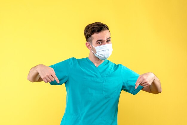 Front view of male doctor with sterile mask on yellow wall