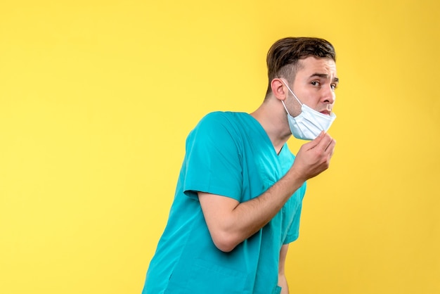 Free photo front view of male doctor with sterile mask on yellow wall