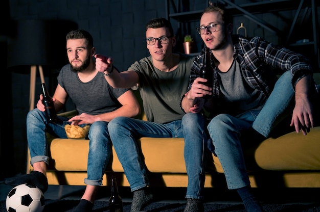 Free photo front view of male friends watching sports on tv together while having snacks and beer