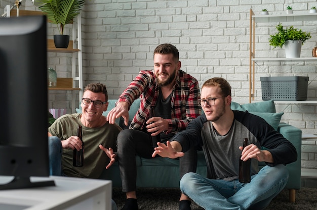 Free photo front view of male friends watching sports on tv together