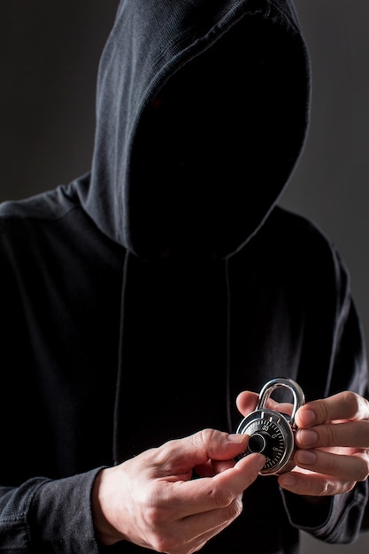 Front view of male hacker holding lock