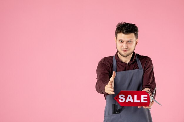 front view male hairdresser with red sale nameplate on pink background