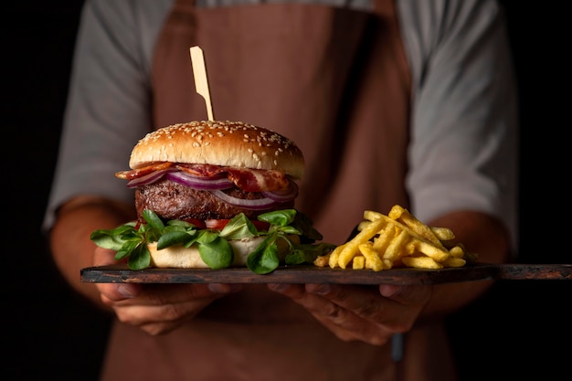 Free photo front view male holding tray with burger and fries