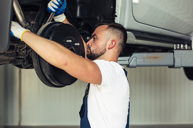 Front view male mechanic changing car wheels