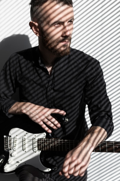 Free photo front view of male musician with electric guitar next to window