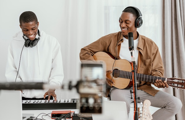 Front view of male musicians at home playing guitar and singing