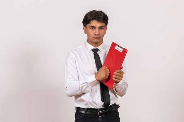 Front view male office worker holding red file on white wall office work human job