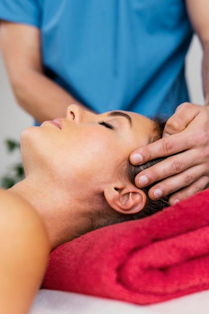 Front view of male osteopathic therapist checking female patient's neck spine