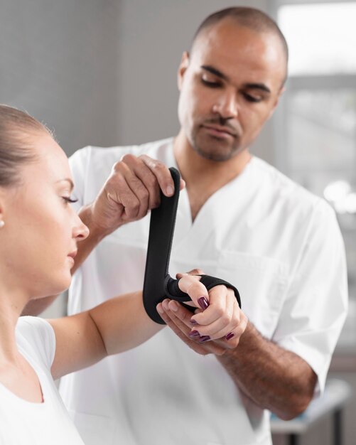 Front view of male physiotherapist wrapping woman's wrist