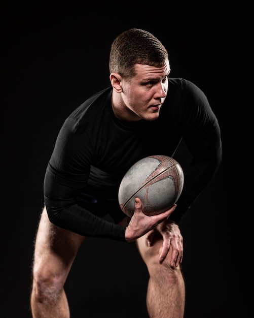 Front view of male rugby player holding ball with one hand