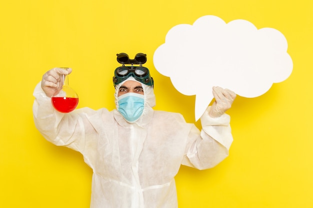 Free photo front view male scientific worker in special protective suit holding flask with red solution and big white sign on the yellow desk