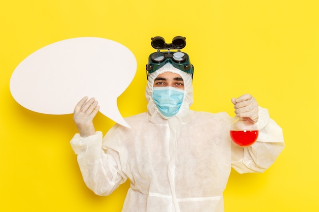 Free photo front view male scientific worker in special protective suit holding flask with red solution and white sign on yellow desk