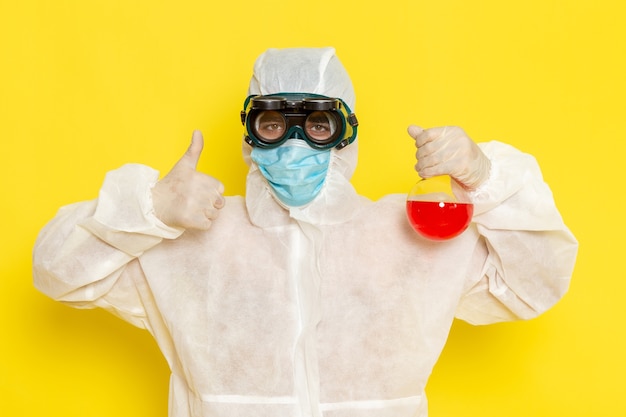 Free photo front view male scientific worker in special protective suit holding flask with red solution on the yellow desk