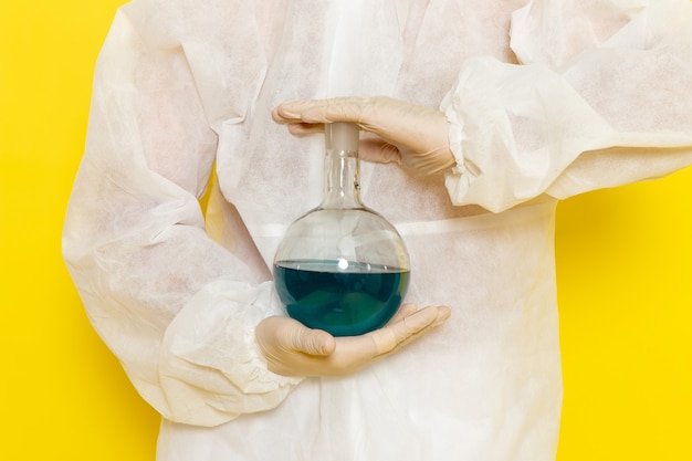 Free photo front view of male scientific worker in special protective suit holding flask with solution on yellow wall