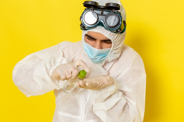 Free photo front view male scientific worker in special protective suit holding spray using it on the yellow surface