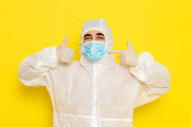 Free photo front view of male scientific worker in special protective white suit with mask on light-yellow wall