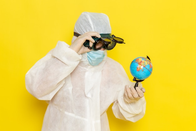 Free photo front view male scientific worker in special suit holding little round globe on yellow desk