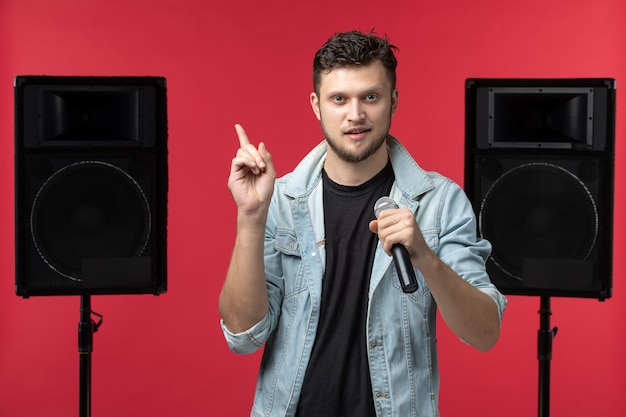 Front view of male singer performing on stage on red wall