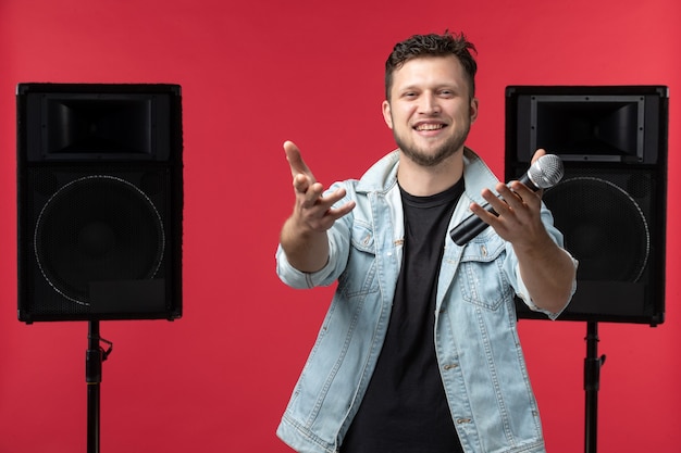 Free Photo front view of male singer performing on stage with mic on a red wall