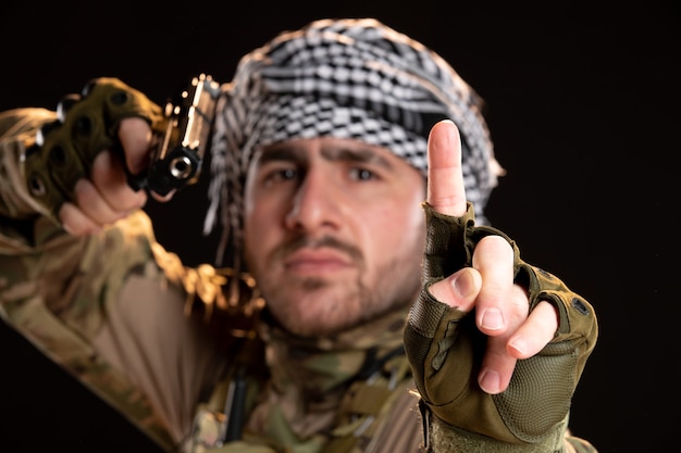 Free Photo front view of male soldier in camouflage aiming gun on black wall