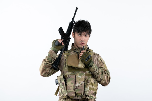 Front view of male soldier in camouflage with machine gun white wall