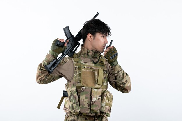 Front view male soldier talking through walkie-talkie in camouflage white wall