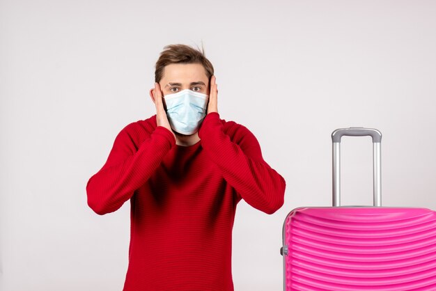 Front view male tourist with pink bag in mask on white wall