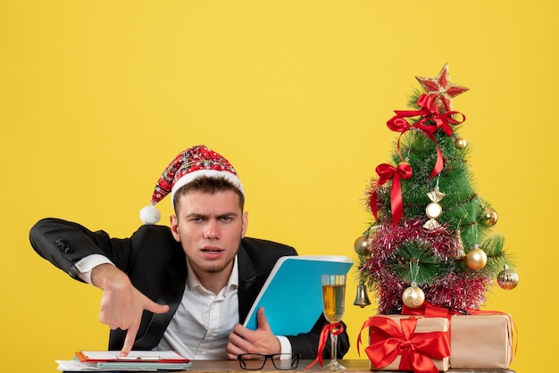 Front view male worker sitting and holding documents on yellow 