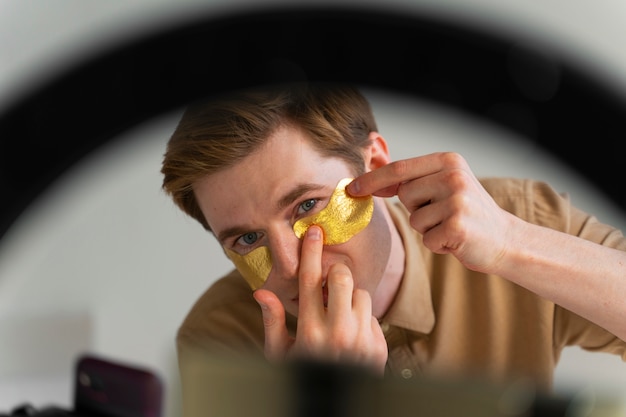 Free photo front view man applying eye patches