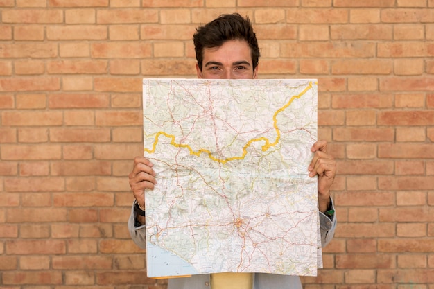 Front view man covering face with a map