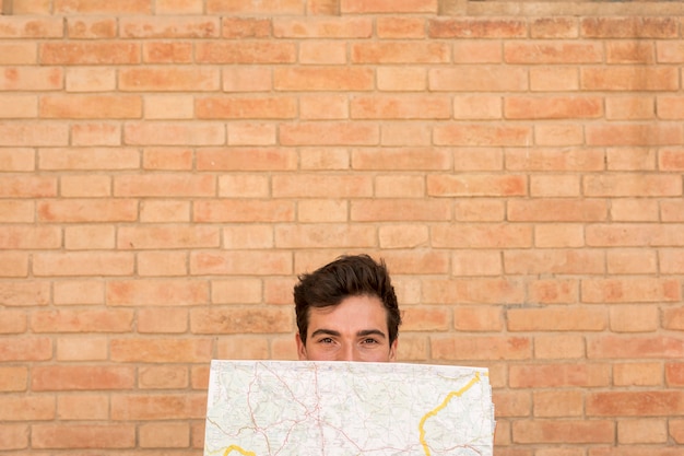 Front view man covering face with a map