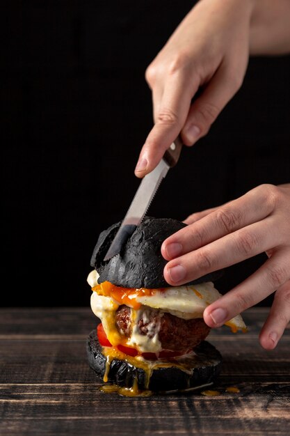 Front view man cutting burger with egg