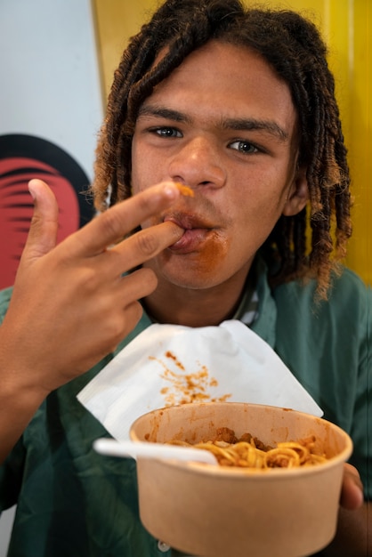 Front view man eating pasta in a funny way