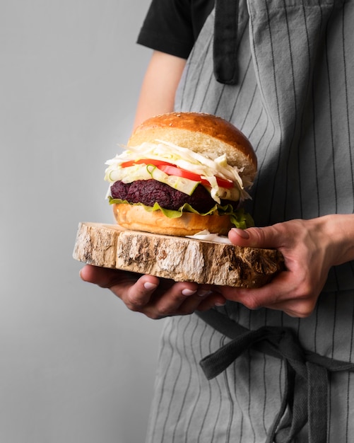 Front view man holding a hamburger on a wooden board