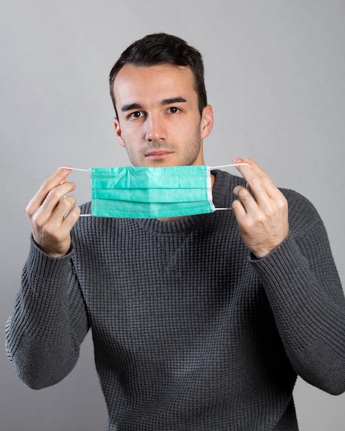 Front view of man holding medical mask with hands