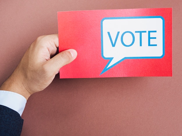 Front view man holding a red card with vote speech bubble 