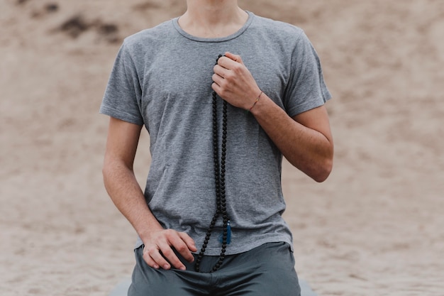 Free Photo front view of man holding rosary outdoors