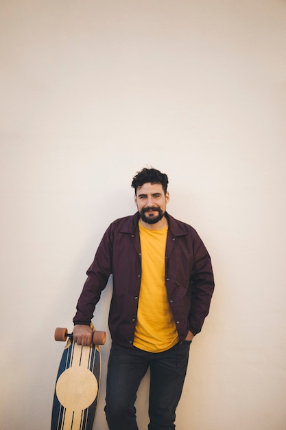 Free Photo front view of man holding skateboard