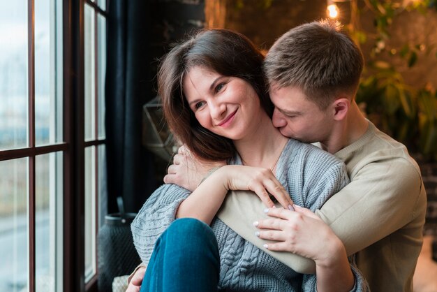 Front view of man kissing smiley girlfriend on the neck