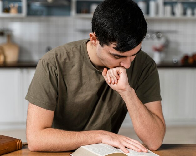 Front view of man in the kitchen reading from the bible