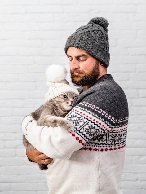 Free photo front view man and kitten wearing fur cap