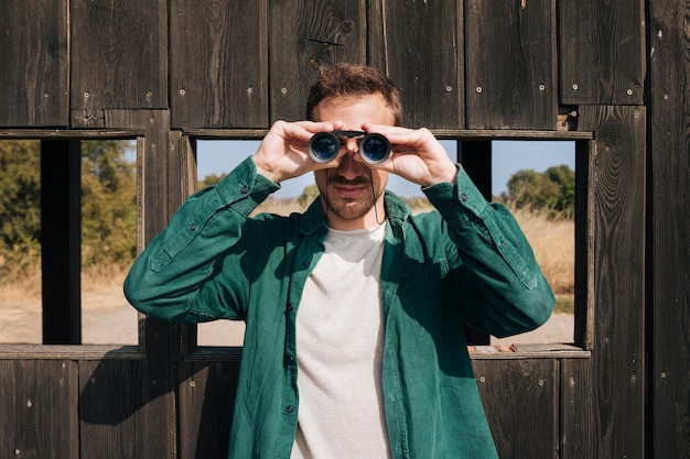 Front view man looking through binoculars